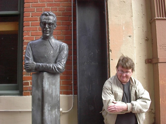 A picture of me next to a bust of Buddy Holly.